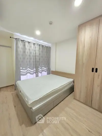 Modern bedroom with wooden flooring and built-in wardrobe, featuring a cozy bed and elegant curtains.