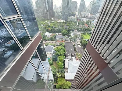 Stunning high-rise city view from a modern skyscraper, showcasing urban landscape and lush greenery below.