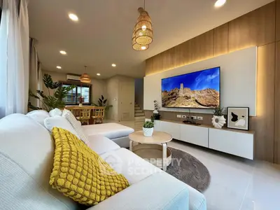 Modern living room with stylish decor and large TV, featuring cozy seating and elegant lighting.