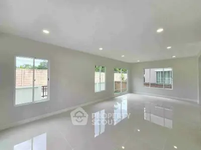 Spacious modern living room with large windows and glossy tiled floors, perfect for natural light and open living.