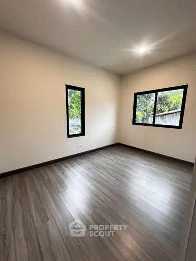 Spacious empty room with large windows and wooden flooring