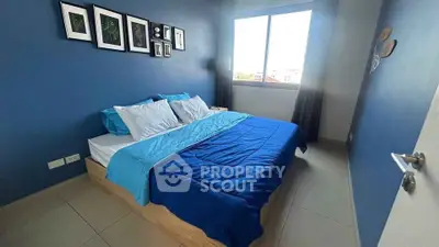 Cozy bedroom with blue accents and wall art, featuring a large window for natural light.