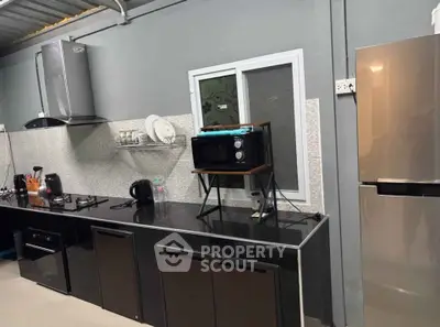 Modern kitchen with sleek black cabinets, stainless steel appliances, and a stylish open layout.