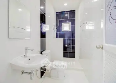 Modern bathroom with sleek white fixtures and spacious shower area.