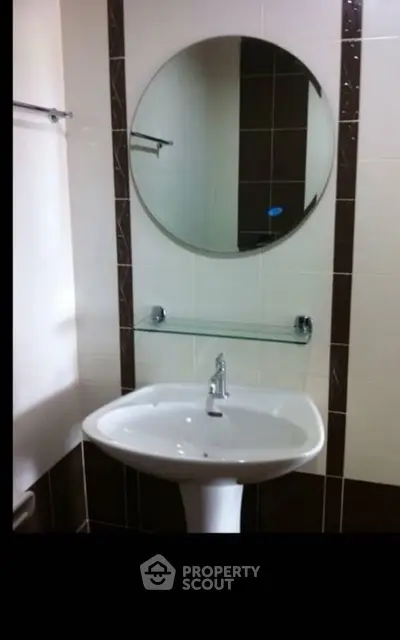 Modern bathroom with sleek pedestal sink and round mirror