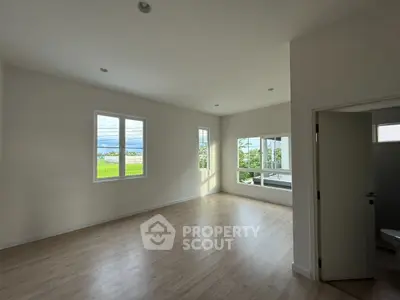 Spacious empty room with large windows and wooden flooring, perfect for customization.