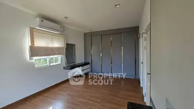 Spacious bedroom with large windows and built-in wardrobe, featuring elegant wooden flooring.
