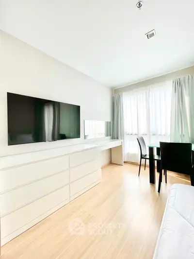 Bright and airy living space with sleek modern furnishings, large windows draped in sheer curtains, and a flat-screen TV for a contemporary lifestyle.