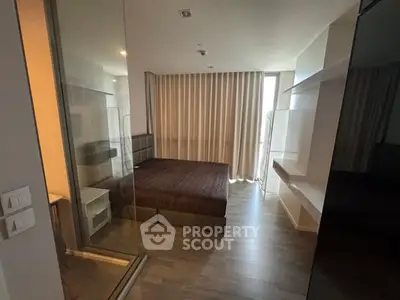 Modern bedroom with glass partition and floor-to-ceiling curtains in a stylish apartment.