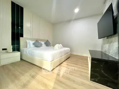 Modern bedroom with sleek design, featuring a large bed, mounted TV, and stylish decor.