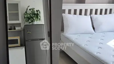 Compact bedroom with adjacent kitchenette featuring fridge and microwave.