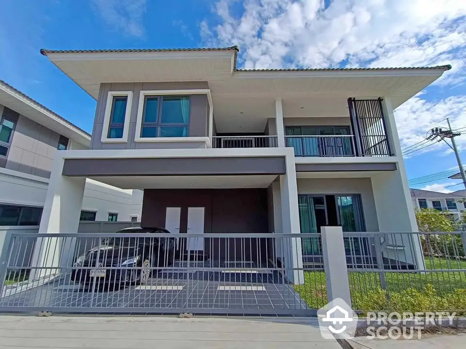 Modern two-story house with sleek design and spacious balcony in a suburban neighborhood.