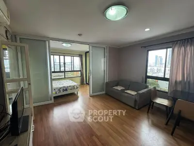 Spacious apartment with wooden flooring, large windows, and a cozy living area in a city setting.