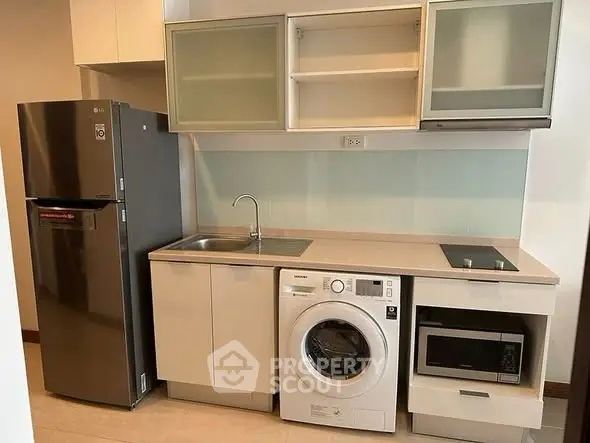 Modern kitchen with sleek appliances including fridge, washing machine, and microwave.