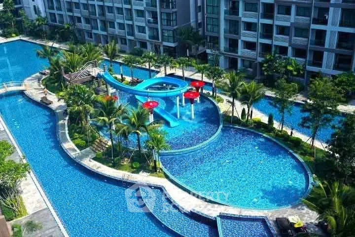 Luxurious residential complex with stunning pool and water slide, surrounded by lush greenery.