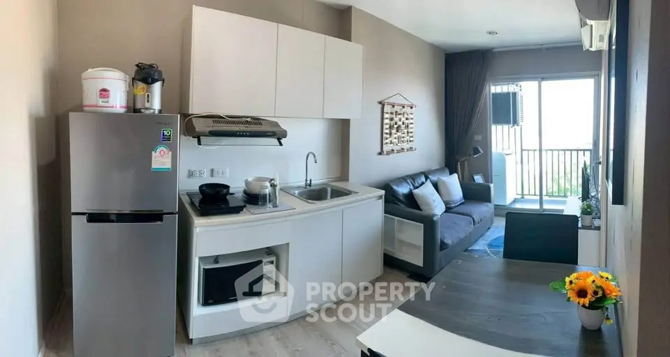 Modern compact kitchen and living area with balcony view in stylish apartment