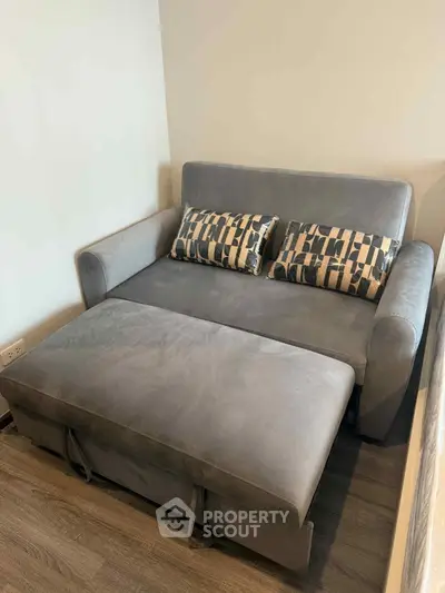 Cozy gray sofa bed with patterned cushions in a modern living room setting.