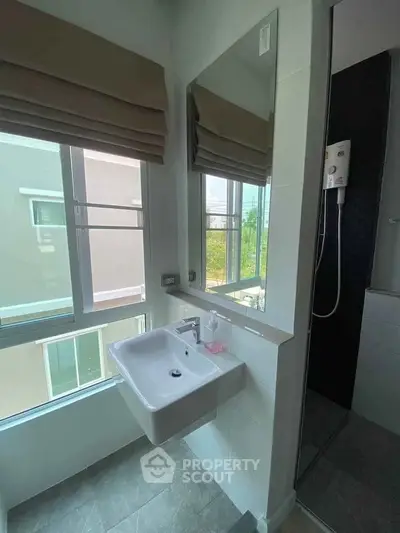 Modern bathroom with sleek sink and large window offering natural light.