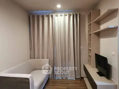 Cozy living room with modern sofa and TV unit, featuring elegant curtains and wooden flooring.