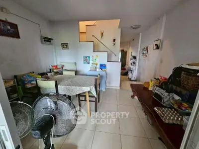 Spacious dining area with tiled flooring and staircase, featuring a fan and dining table.