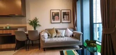 Modern living room with cozy sofa and dining area, featuring large windows and stylish decor.