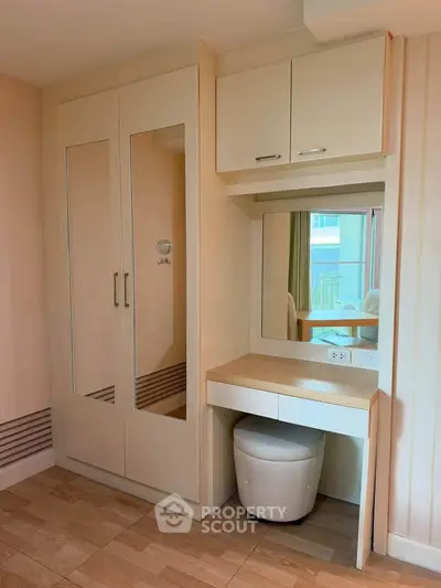 Modern bedroom with built-in wardrobe and vanity in a stylish apartment.