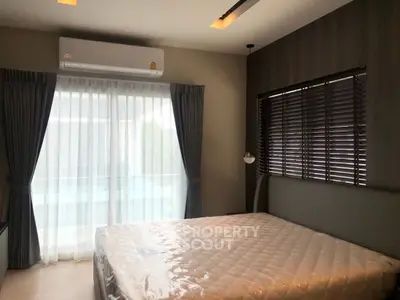 Modern bedroom with large window and air conditioning, featuring stylish curtains and blinds.