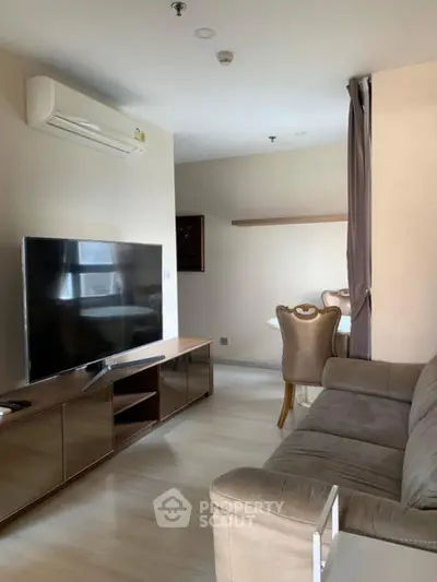 Modern living room with sleek furniture and large TV in a cozy apartment setting.
