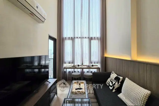 Modern living room with high ceilings and large windows, featuring stylish furniture and a sleek TV setup.