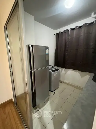 Compact kitchen with modern fridge and washing machine, ideal for efficient living.