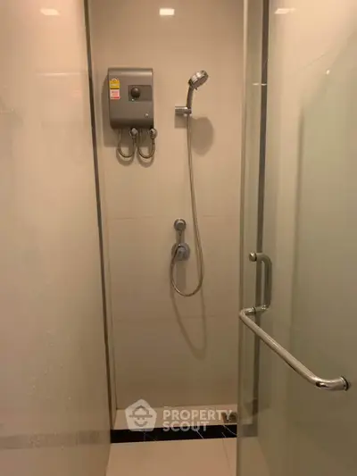Modern bathroom shower area with sleek glass door and wall-mounted showerhead.