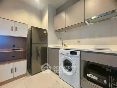 Modern kitchen with sleek cabinets, fridge, and washing machine in a compact layout.