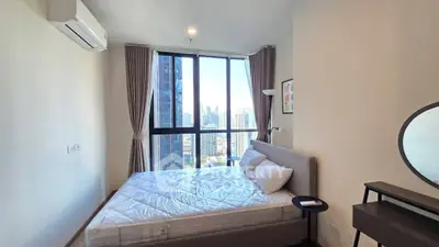 Modern bedroom with city view, featuring large windows and stylish decor.