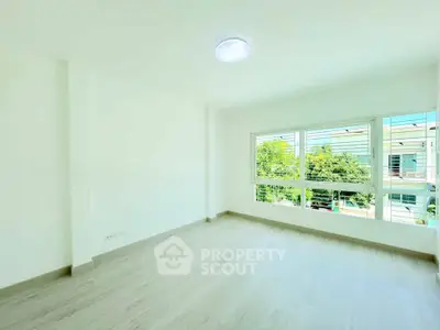 Bright and spacious empty room with large windows and wooden flooring, perfect for customization.