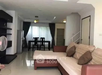 Spacious living room with modern sofa and dining area, perfect for family gatherings.