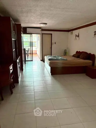 Spacious bedroom with large windows and balcony access in modern apartment.