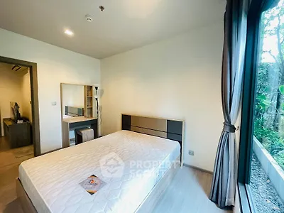 Spacious bedroom with large window and modern furnishings in a serene setting.