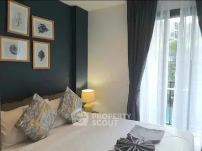 Cozy bedroom with elegant decor and balcony view in modern apartment.