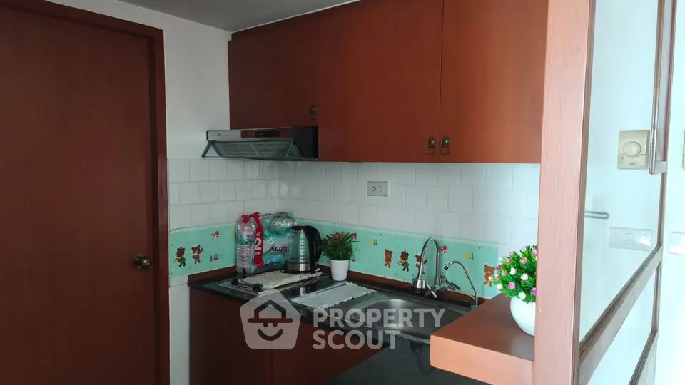 Charming compact kitchen with wooden cabinets and modern appliances in cozy apartment.
