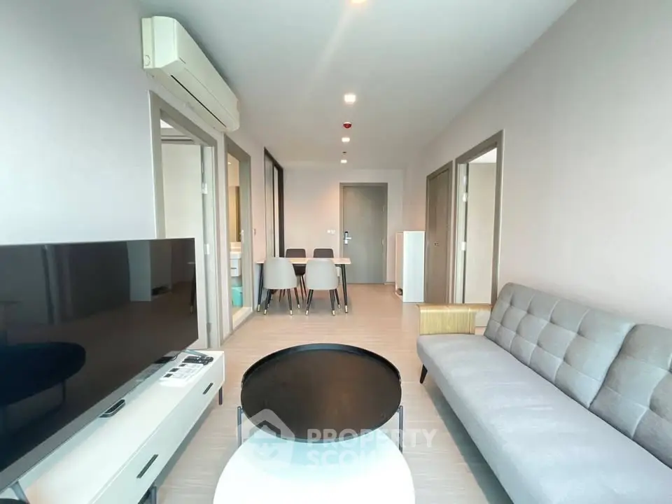 Modern living room with sleek furniture and open layout, featuring a stylish sofa and dining area.