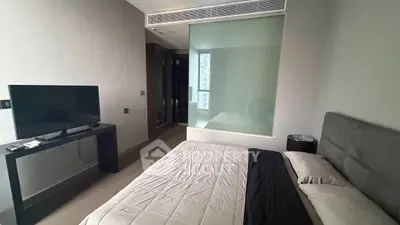 Modern bedroom with sleek design, featuring a comfortable bed and flat-screen TV, ideal for urban living.