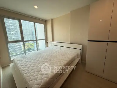 Modern bedroom with large window and sleek wardrobe in a high-rise apartment.