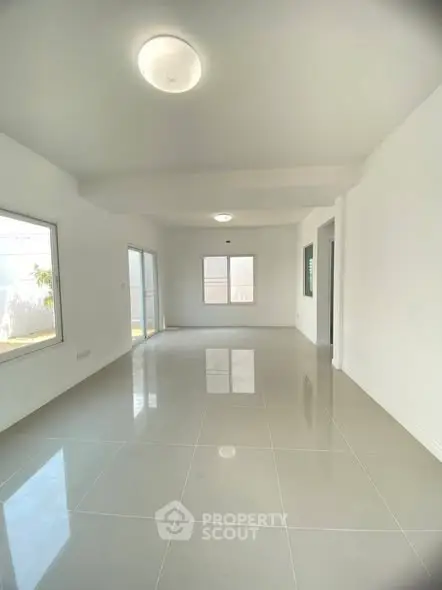 Spacious and bright living room with large windows and glossy tiled floors, perfect for modern living.