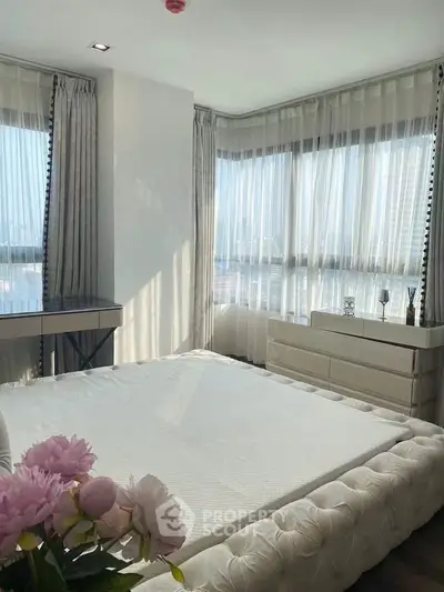 Luxurious bedroom with large windows and elegant decor, offering a serene and bright atmosphere.