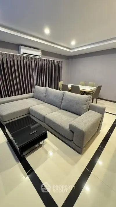 Modern living room with sleek gray sofa and elegant dining area