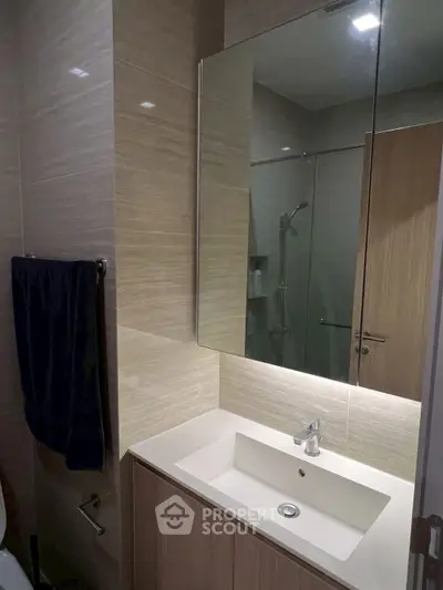 Modern bathroom with sleek vanity and large mirror in contemporary apartment.