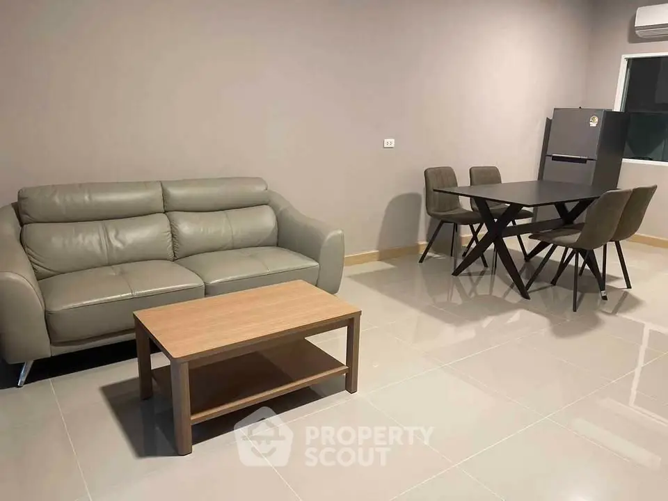 Modern living room with sleek furniture and dining area, featuring a stylish sofa and table set.