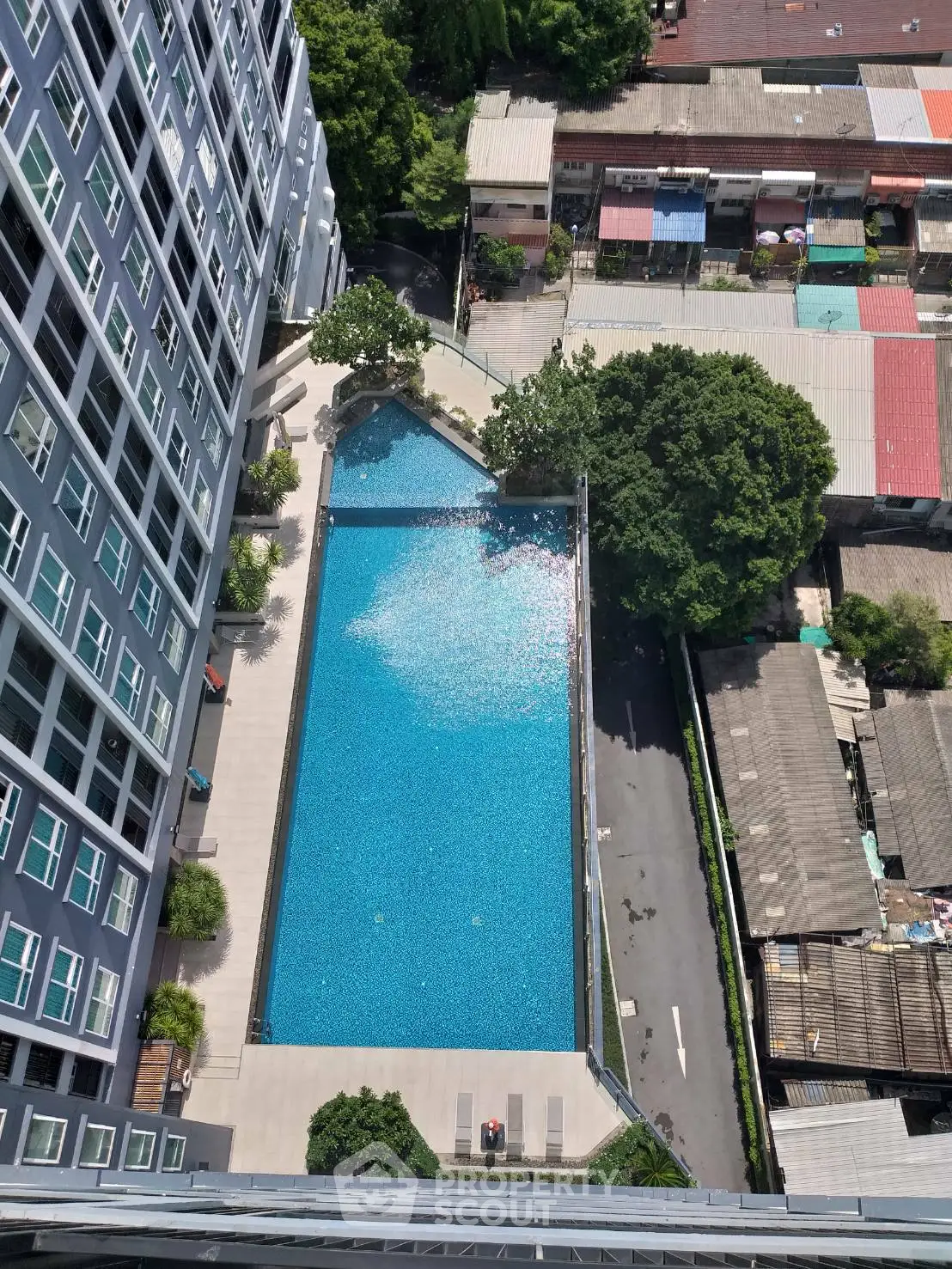 Stunning aerial view of modern condominium with sparkling pool and lush greenery, perfect for urban living.