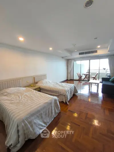 Spacious bedroom with twin beds and balcony access in modern apartment