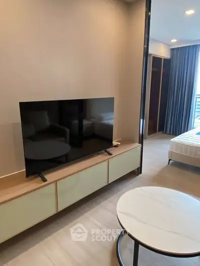 Modern living room with sleek TV setup and cozy bedroom view